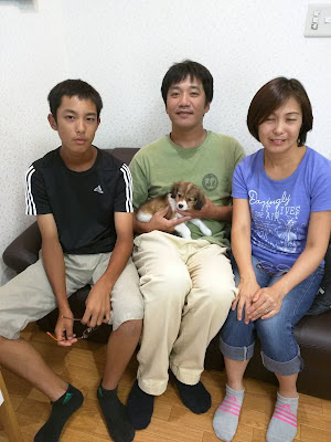 家族と子犬がソファに座っている写真です。.