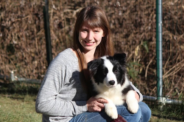 若き王子様と黒白の犬の写真、笑顔で屋外にいる女性と犬の親密な瞬間.