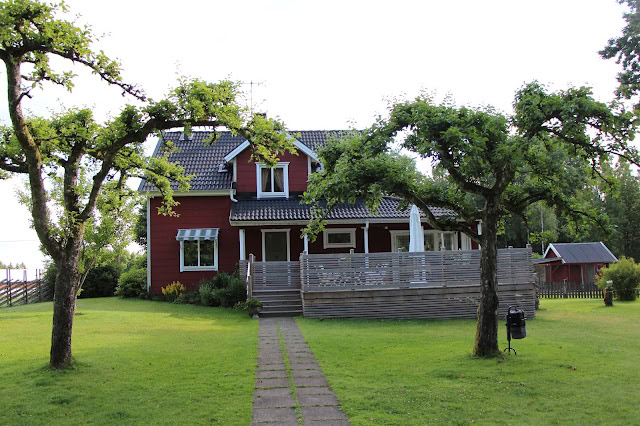 家の前の緑豊かな庭と木々に囲まれた赤い家.