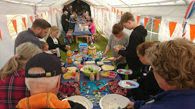 屋外のテント内で人々が食事を楽しむ様子を写した写真です。.