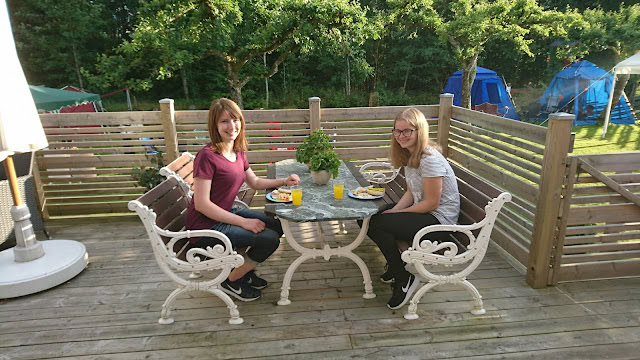 屋外の木製デッキで友人とお茶を楽しむ二人の女性.