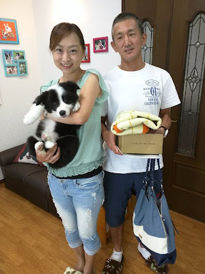 犬を抱く女性と荷物を持つ男性の笑顔の家族写真.