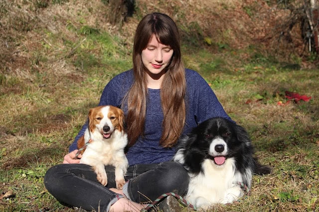 女性と2匹の犬が自然の中でリラックスしている写真.